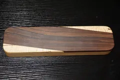 Rectangular clapper with a dark rosewood panel running diagonally across curly maple
