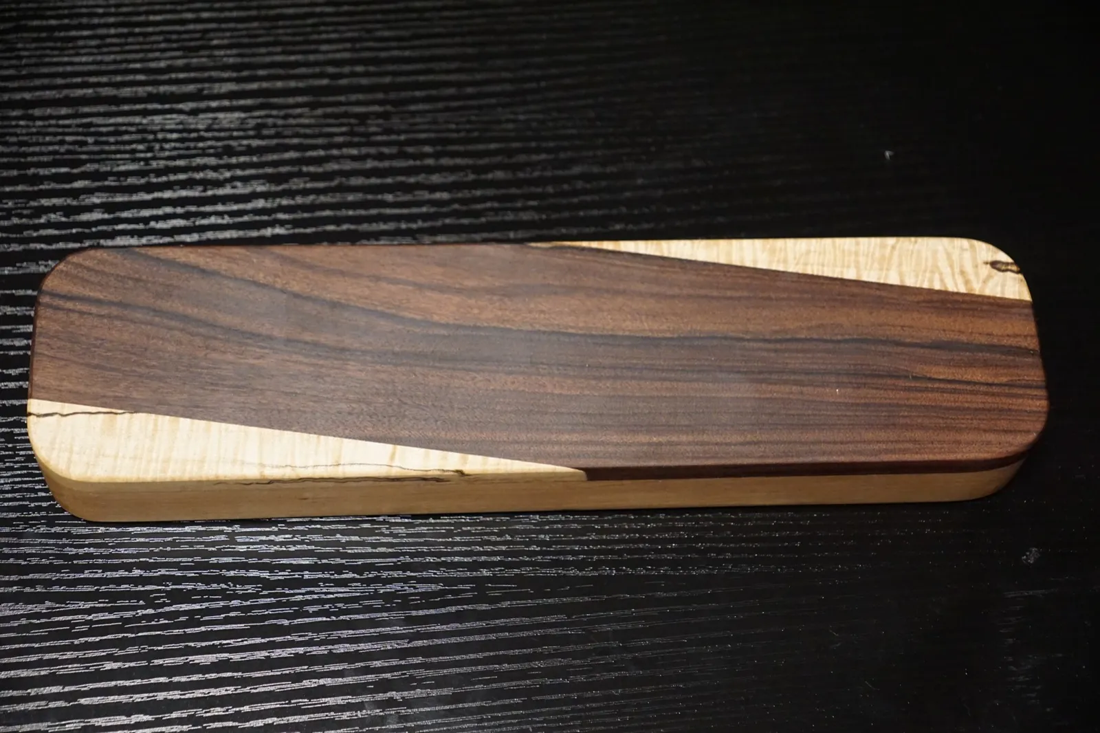 Rectangular clapper with a dark rosewood panel running diagonally across curly maple