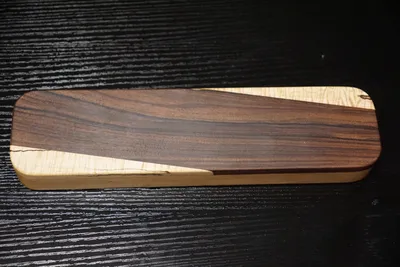 Rectangular clapper with a dark rosewood panel running diagonally across curly maple