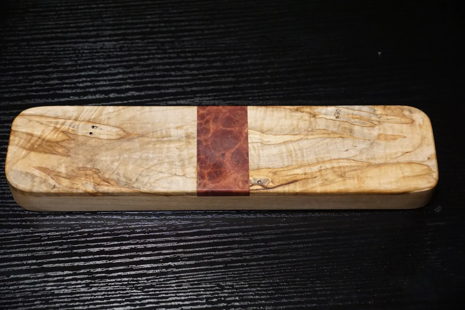 Rectangular clapper of spalted curly maple with a red mallee burl band across the center