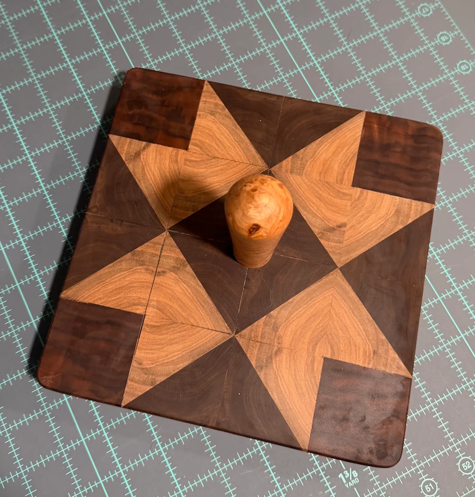 Square clapper pieced from walnut and maple triangles in a star quilt block, with a turned maple burl knob at the center
