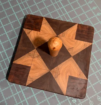 Square clapper pieced from walnut and maple triangles in a star quilt block, with a turned maple burl knob at the center